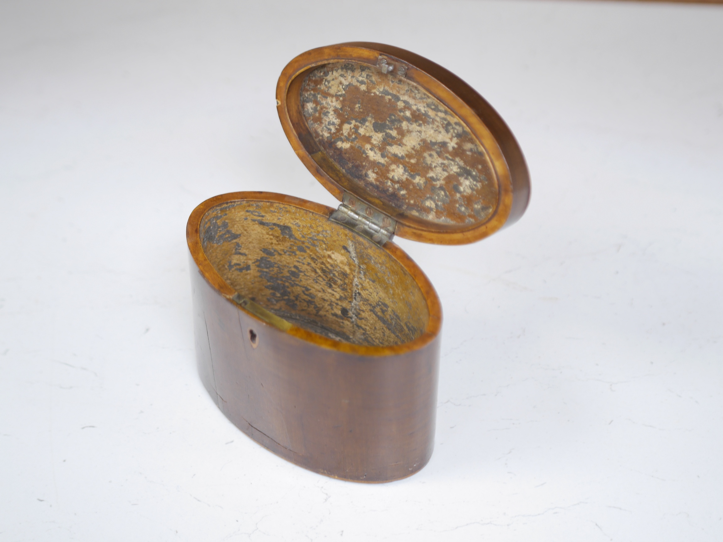 A George III oval inlaid sycamore tea caddy, 12cm high x 15cm wide. Condition - two splits to front.